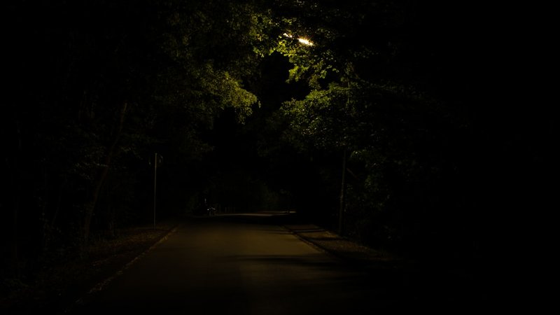 夜の公道で酒に酔って歩いている人物のイメージ